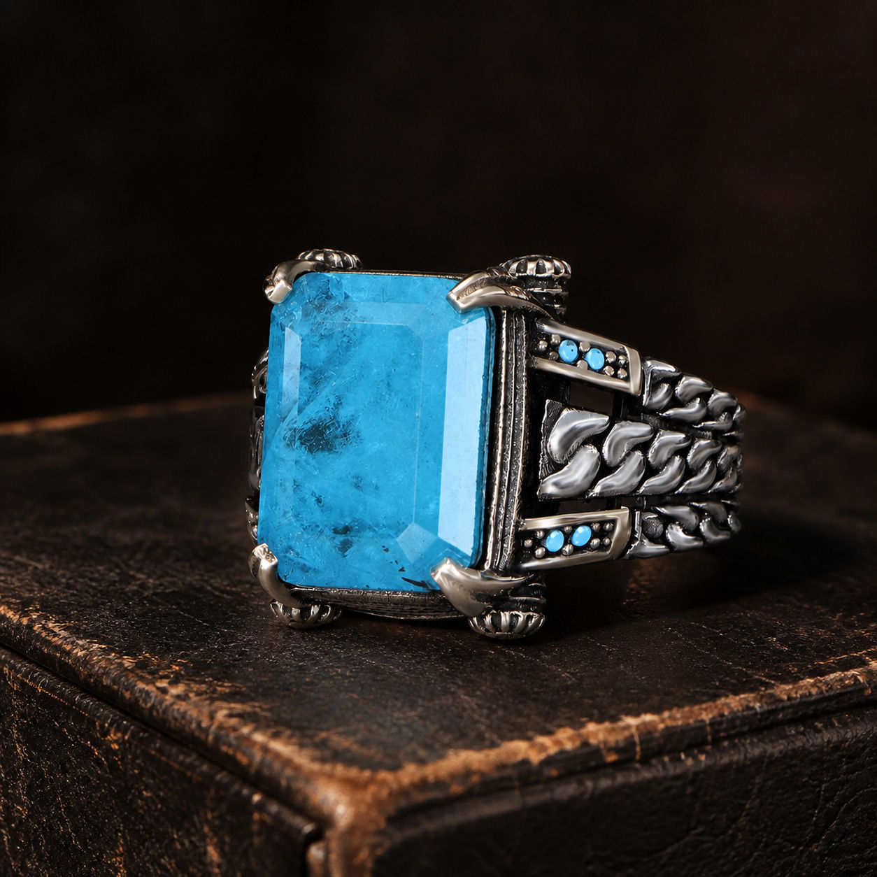 Blue Paraiba Braided Chain Sterling Silver Men's Ring displayed on a black leather antique book