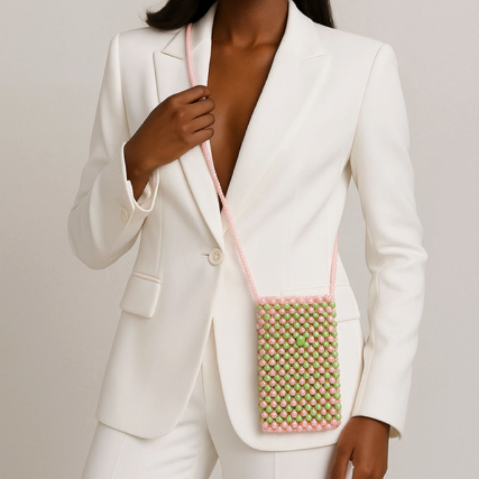 Beautiful woman in white pant suit with pink and green beaded pearl crossbody phone holder