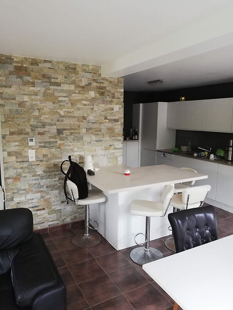 Mur en briques apparentes de style industriel avec îlot central en bois, apportant chaleur, contraste et fonctionnalité à une cuisine rénovée.