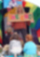 Storyteller Amanda Kane-Smith smiles down at children who are watching her story. She is holding a The End storytelling banner.jpg