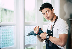 carpenter-holds-drill-drills-window.jpg