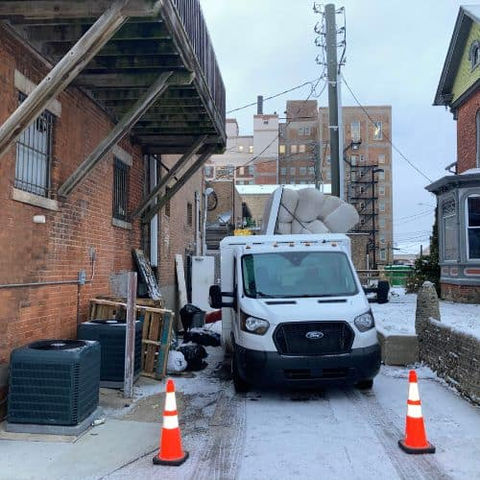 White utility van in snowy alley with traffic cones