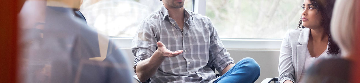A man seated and gesturing during a conversation.
