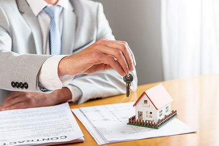 person-holding-house-keys-toy-model-house-desk.jpg