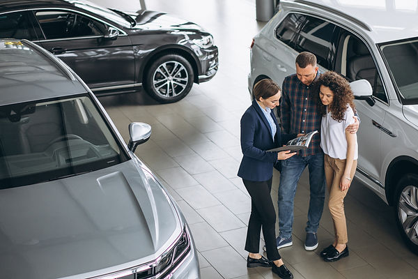 young-couple-talking-sales-person-car-showroom (1).jpg