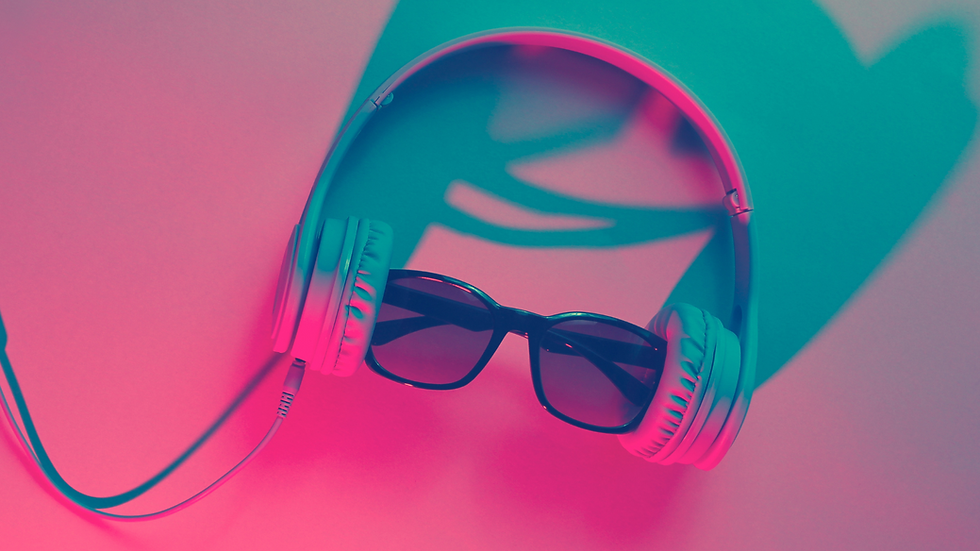 Audifonos alámbrios con unos lentes negros en medio sobre un fondo liso y luces neon proyectadas