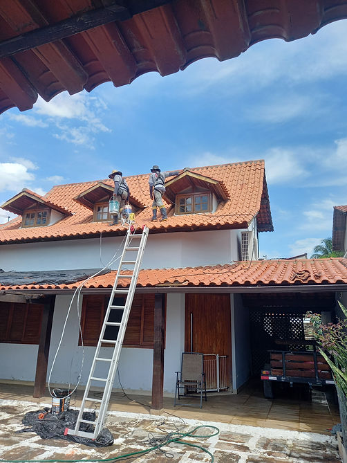 Duas pessoas limpando o telhado de uma casa