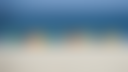 The image of five colorful umbrellas hovering over a long stretch of sand with a calm sea just beyond was taken by Nick Fewings.