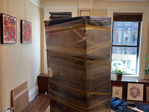 VoltoVerse Movers carefully wrapping and maneuvering furniture in a small Manhattan apartment.