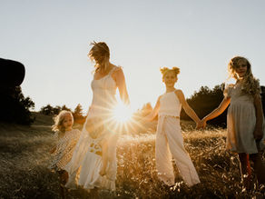 A MOTHER AND HER DAUGHTERS HOLD HANDS DURING A FAMILY PHOTOGRAPHY SESSION IN PETALUMA