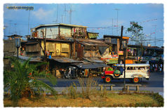 Colourful jeepney passing roadside stalls and simple dwellings in Manila, with tangled wires in warm late-afternoon light, Philippines