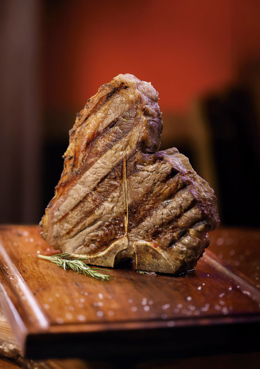 Bife grelhado na tábua de madeira com alecrim e textura, cruzeirosprime