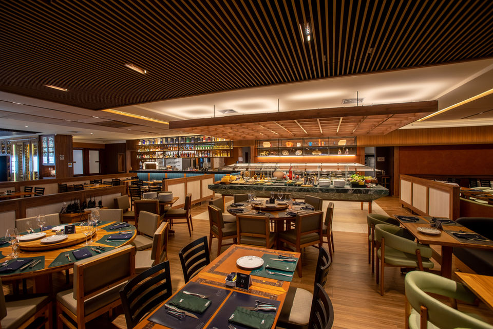 Restaurante interno com mesas, buffet e iluminação ambiente. cruzeirosprime