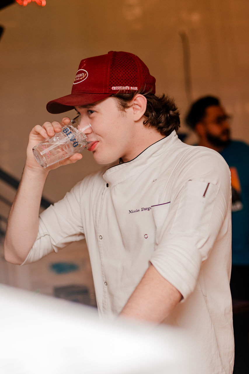 Chef bebendo água em um copo, usando chapéu e uniforme, bolovo.