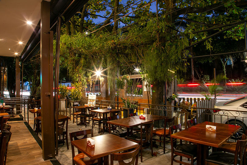 Mesas e cadeiras de restaurante ao ar livre, com iluminação noturna caetanos.