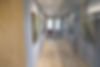 Foto do corredor do escritorio com quadros de arte na esquerda e slas de reuniião e trabalho na doireite fundo