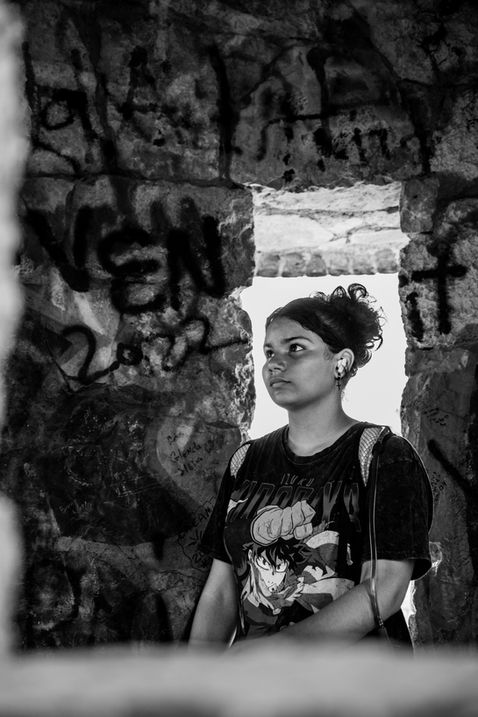 Woman standing pensively near graffiti-covered stone wall