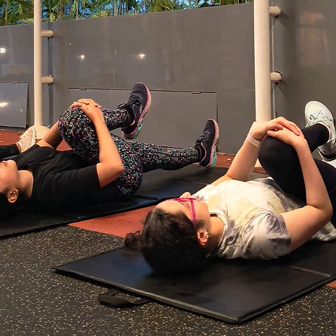 Two girls stretching on mats during JuniorFit fitness class