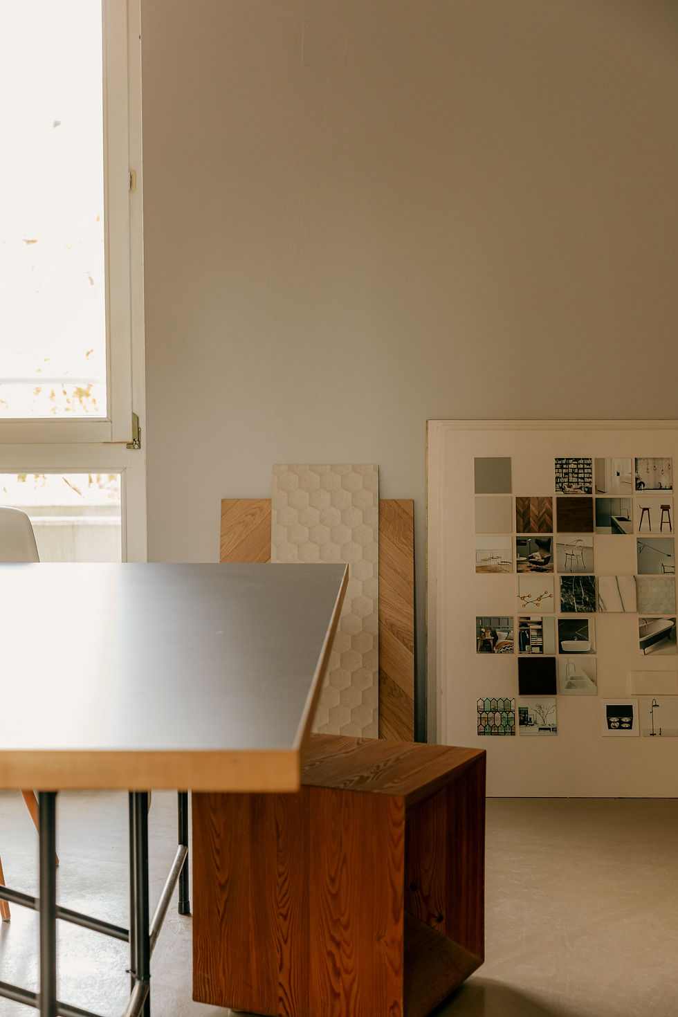 Heller Arbeitsraum mit großem Tisch, Sitzmöbel, Materialmustern und Moodboard für unterschiedliche kreative Tätigkeiten.