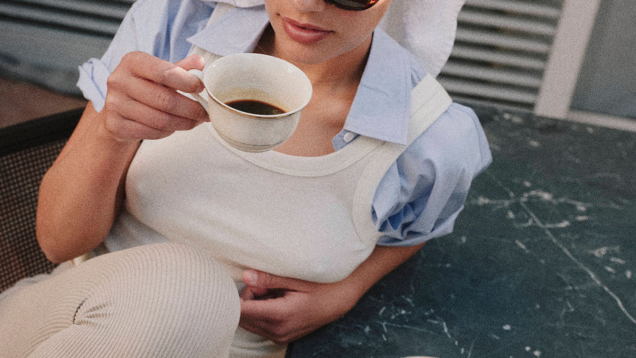 Frau mit Sonnenbrille und Handtuch im Haar trinkt Kaffee an einem dunklen Marmortisch – atmosphärische Inszenierung von Hospitality und Aufenthaltsqualität.