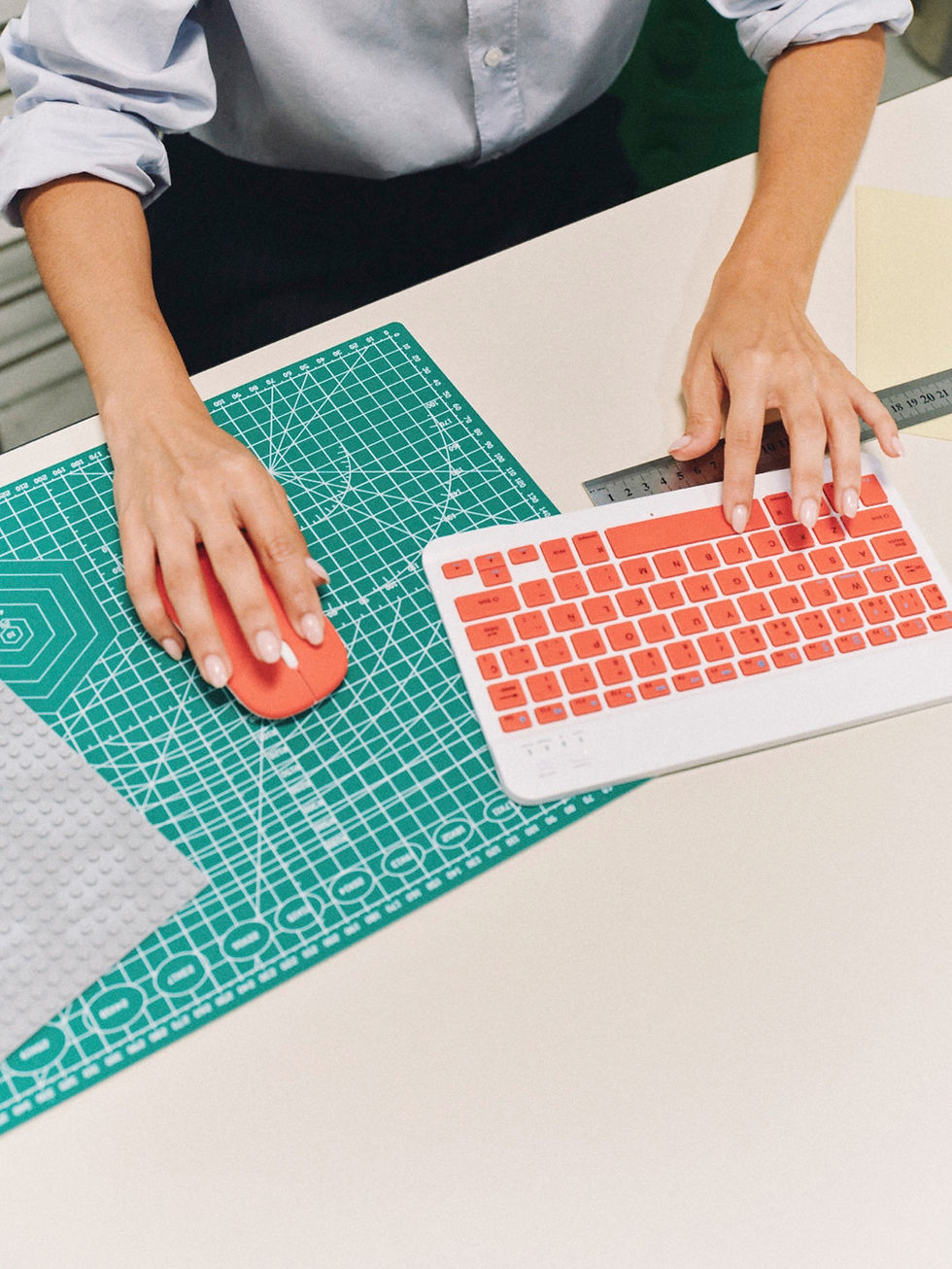 Designerin arbeitet mit Computer, Lineal und Schneidematte an einem Gestaltungskonzept.