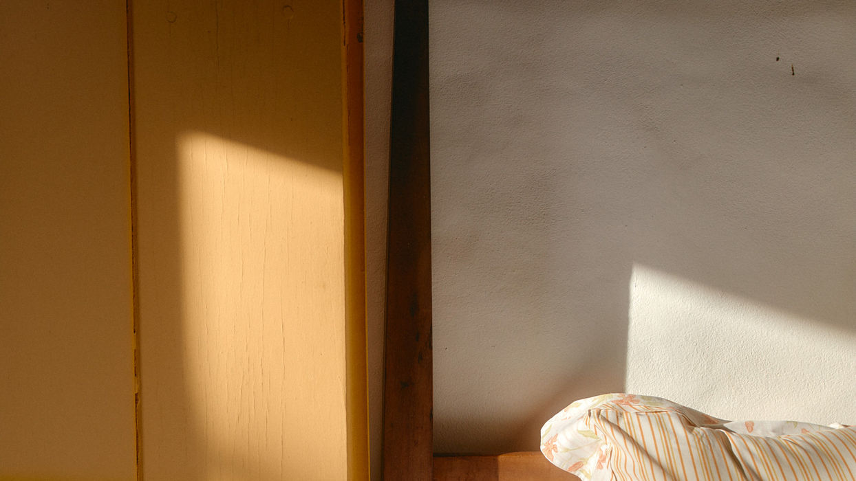 Innenraum mit Bett, Holzelementen und einfallendem Sonnenlicht als Beispiel für räumliche Tiefe, Flächen und Perspektive.