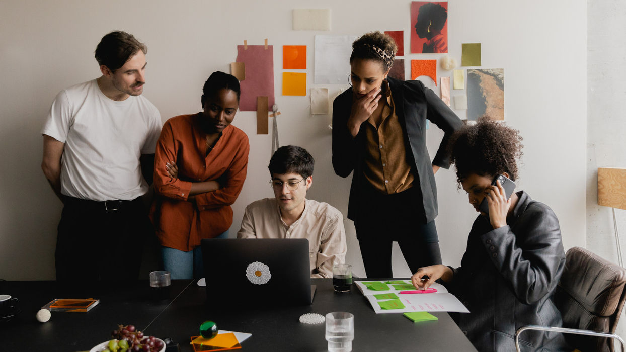 Kreativteam bei der gemeinsamen Konzeptentwicklung mit Laptop, Materialmustern und Moodboard in einem Planungsbüro.