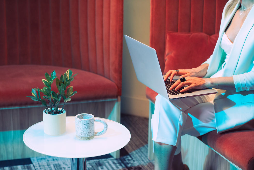 Home Stagerin arbeitet mit Laptop in einem farblich inszenierten Interior mit roten Polstermöbeln – Planung und Konzeption professioneller Raumgestaltung.