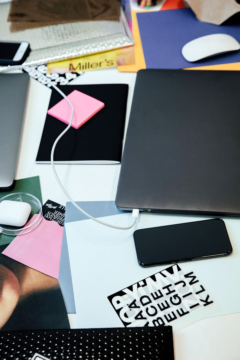 Kreativer Arbeitsplatz mit Laptop, Materialien und Notizen als Teil eines vielseitigen Entwurfsprozesses.