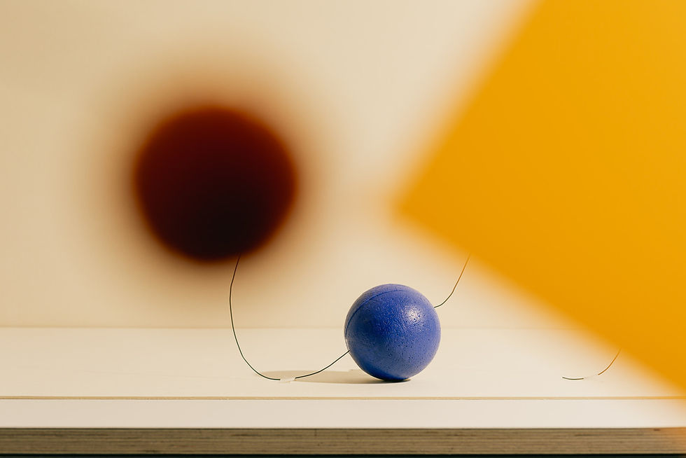 Blaue Kugel vor einer hellen Fläche mit großflächigem orangefarbenem Licht und Schatten als Beispiel für die Wirkung von Farbkontrasten im Raum.