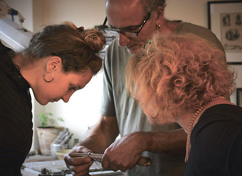 Rafi Hayon showing two people how to measure a ring they are making.