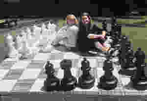 Catina O'Leary and Amy Waterman sit back to back on a life-size chess board, surrounded by large chess pieces