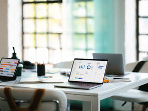 An office workspace with laptops displaying analytics, surrounded by other office items, symbolizing productivity, technology, and business collaboration.