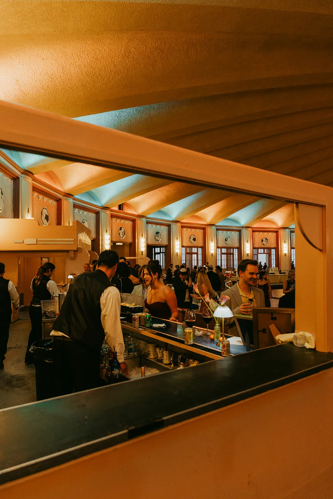 Guests at the Casino Ballroom bar during cocktail hour at a Catalina Island Casino wedding, warm amber uplighting and art deco interior