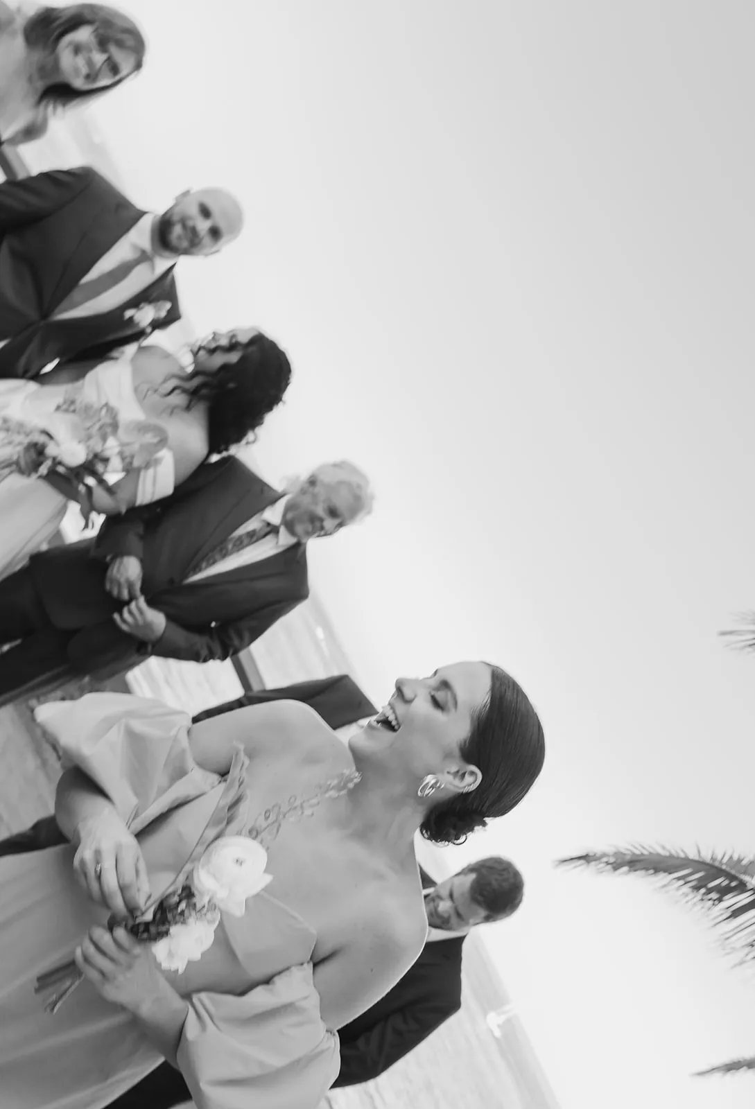 Candid black and white moment of the bridal party laughing together at the Catalina Island Casino wedding, shot from a creative angle