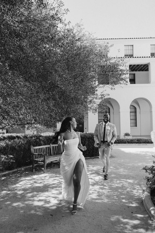 Black and white photo of the bride walking alone along a garden path at Pasadena City Hall
