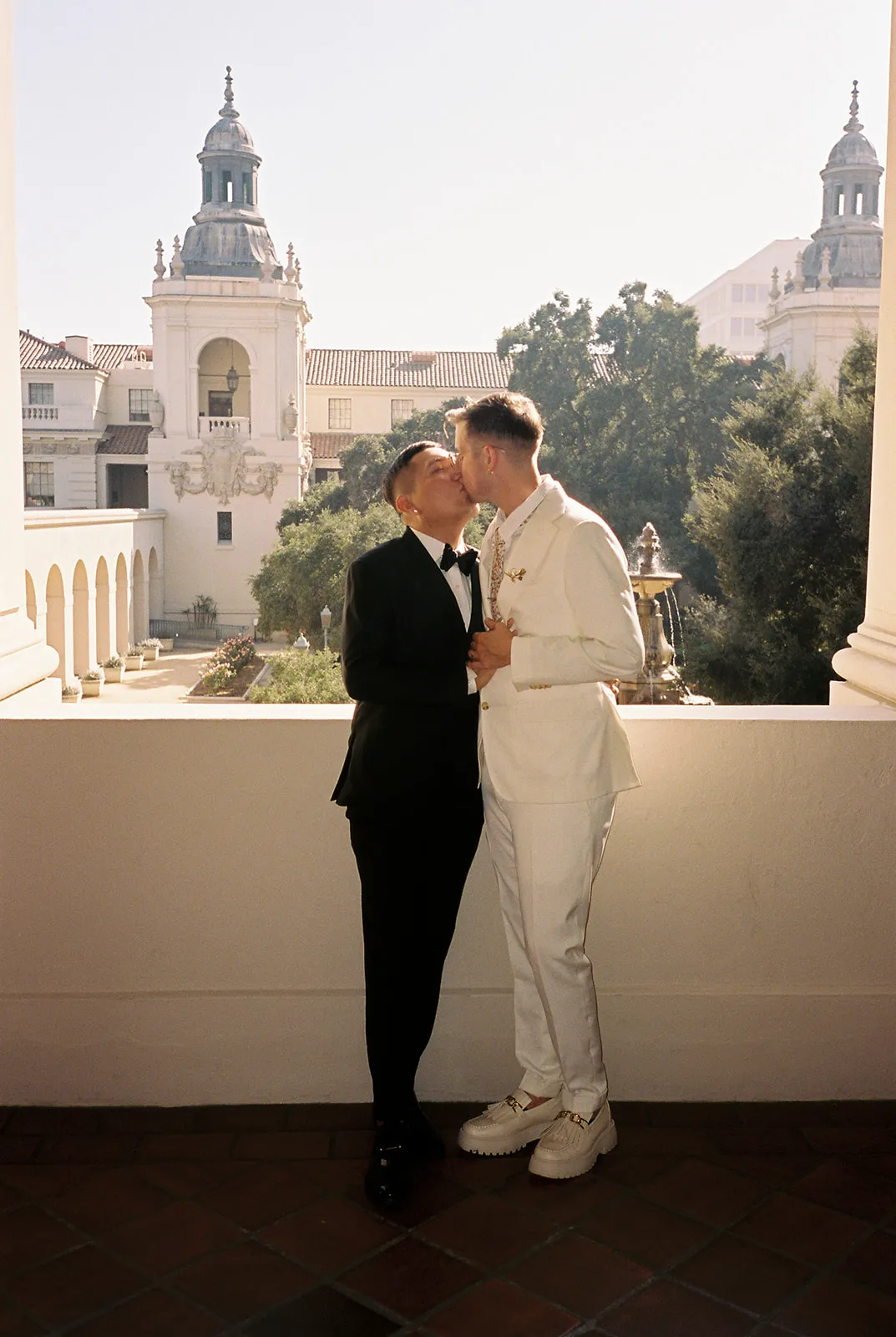 Couple kissing on the second-floor balcony at Pasadena City Hall with the dome tower visible below