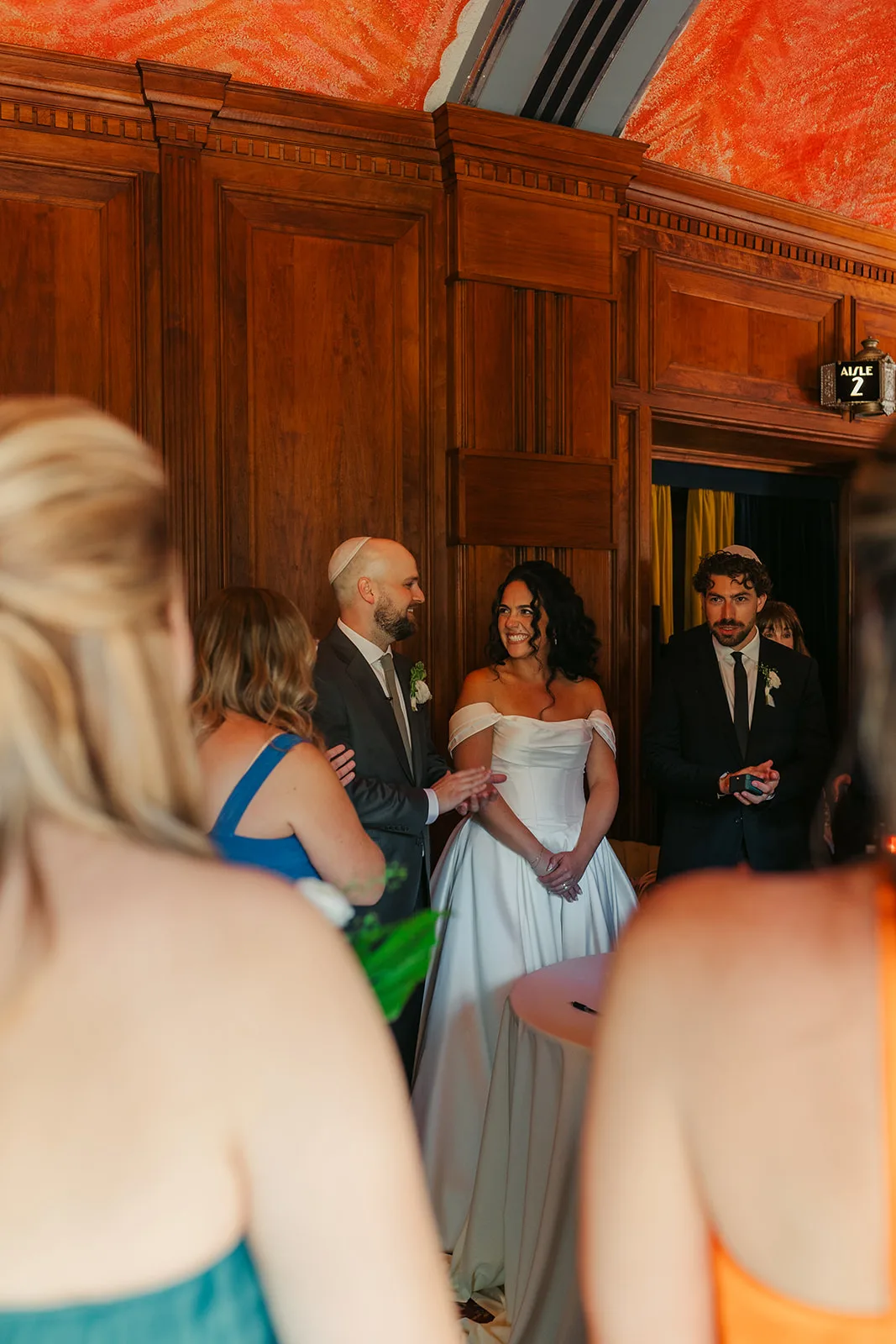 Wedding party celebrating after the ketubah signing inside the Catalina Island Casino before the ceremony, warm wood-paneled room