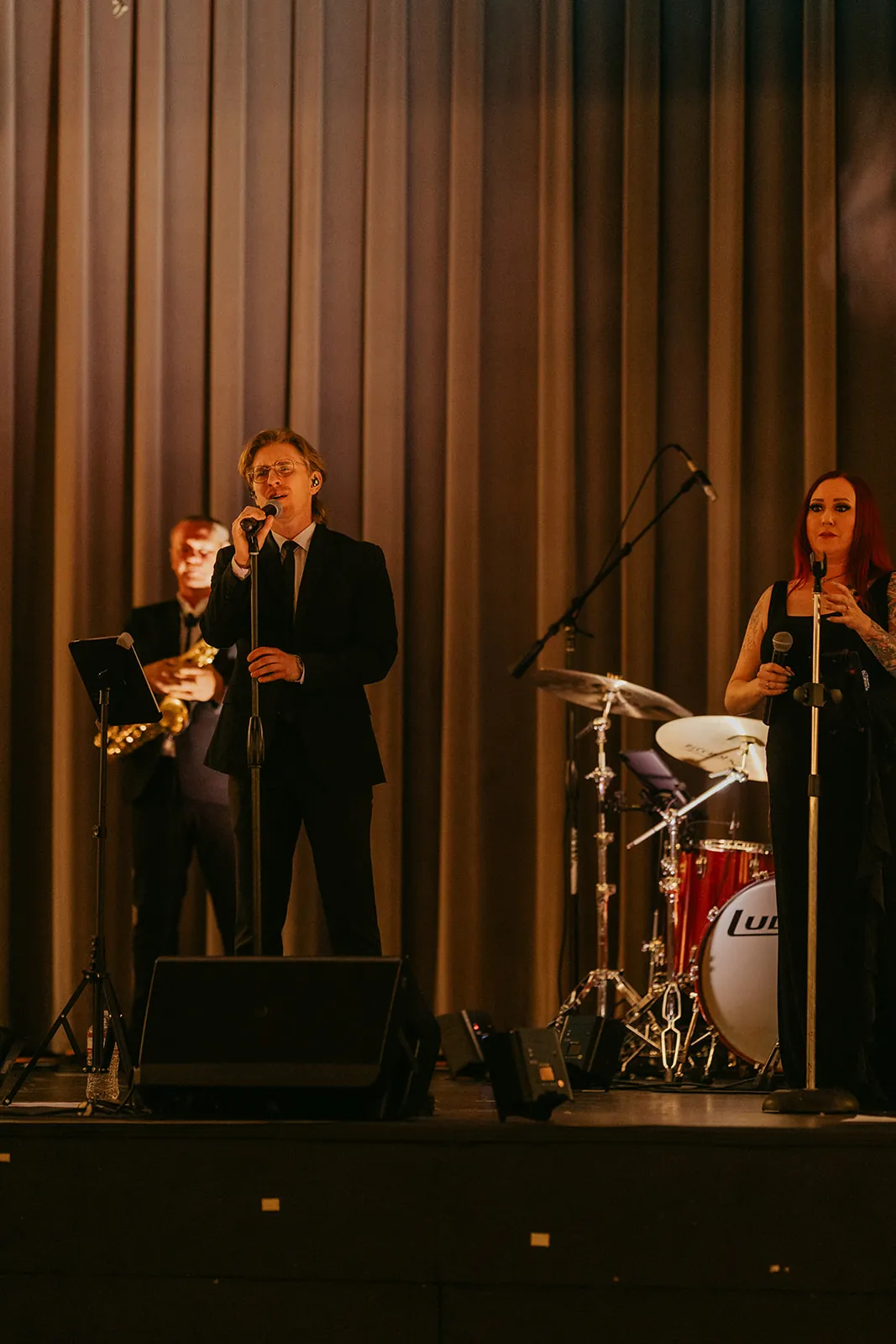 Live band performing on the Catalina Island Casino Ballroom stage during the wedding reception — lead vocalist, saxophonist, and drummer