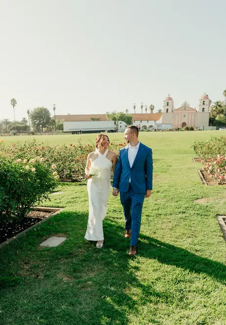 Wide portrait of bride and groom on the Sunken Gardens lawn with the Santa Barbara courthouse beyond