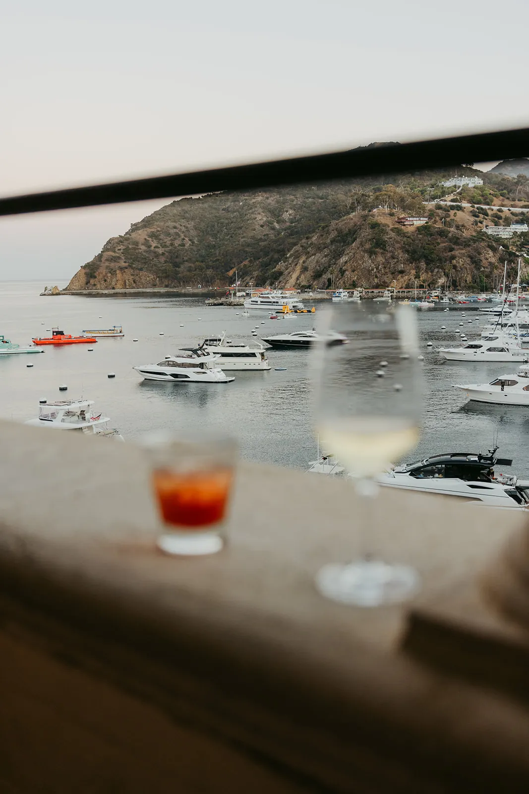 Cocktails resting on the Casino veranda railing overlooking Avalon Bay during a Catalina Island Casino wedding cocktail hour, with boats and island hills in the background