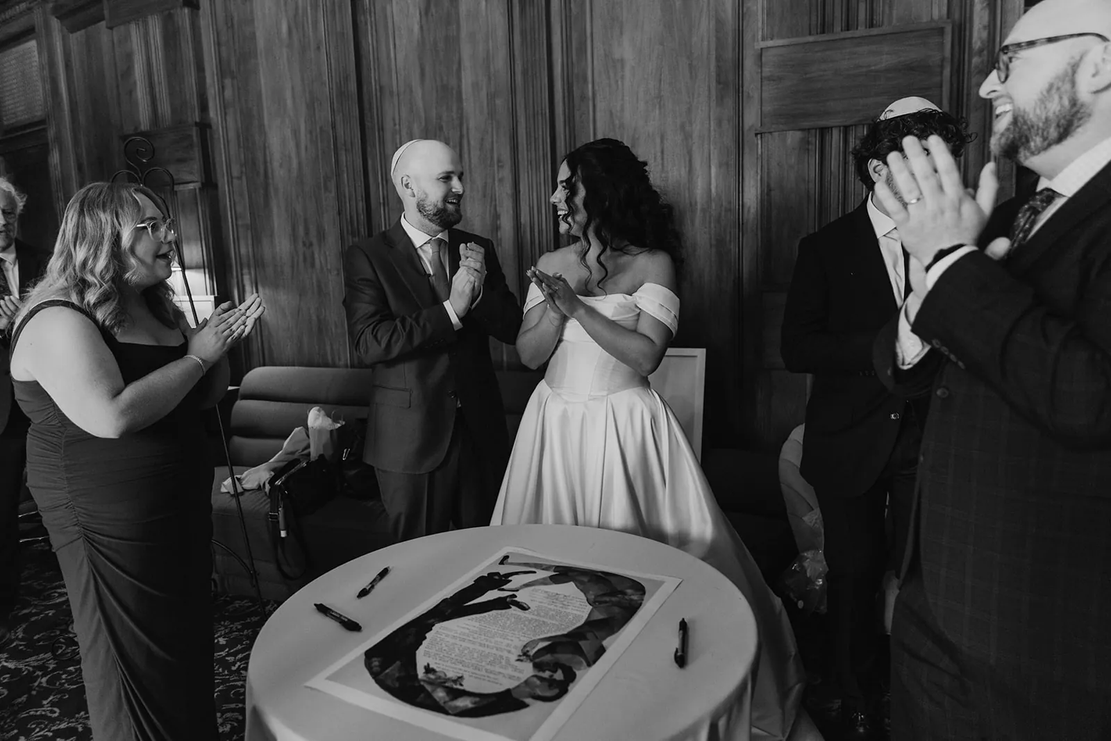 Couple celebrating after signing the ketubah inside the Catalina Island Casino before their wedding ceremony, candid black and white moment