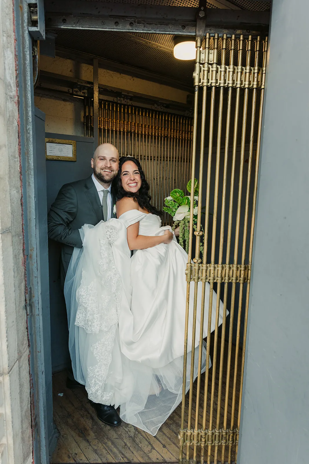 Bride and groom laughing together inside the ornate gold cage elevator at the Catalina Island Casino on their wedding day