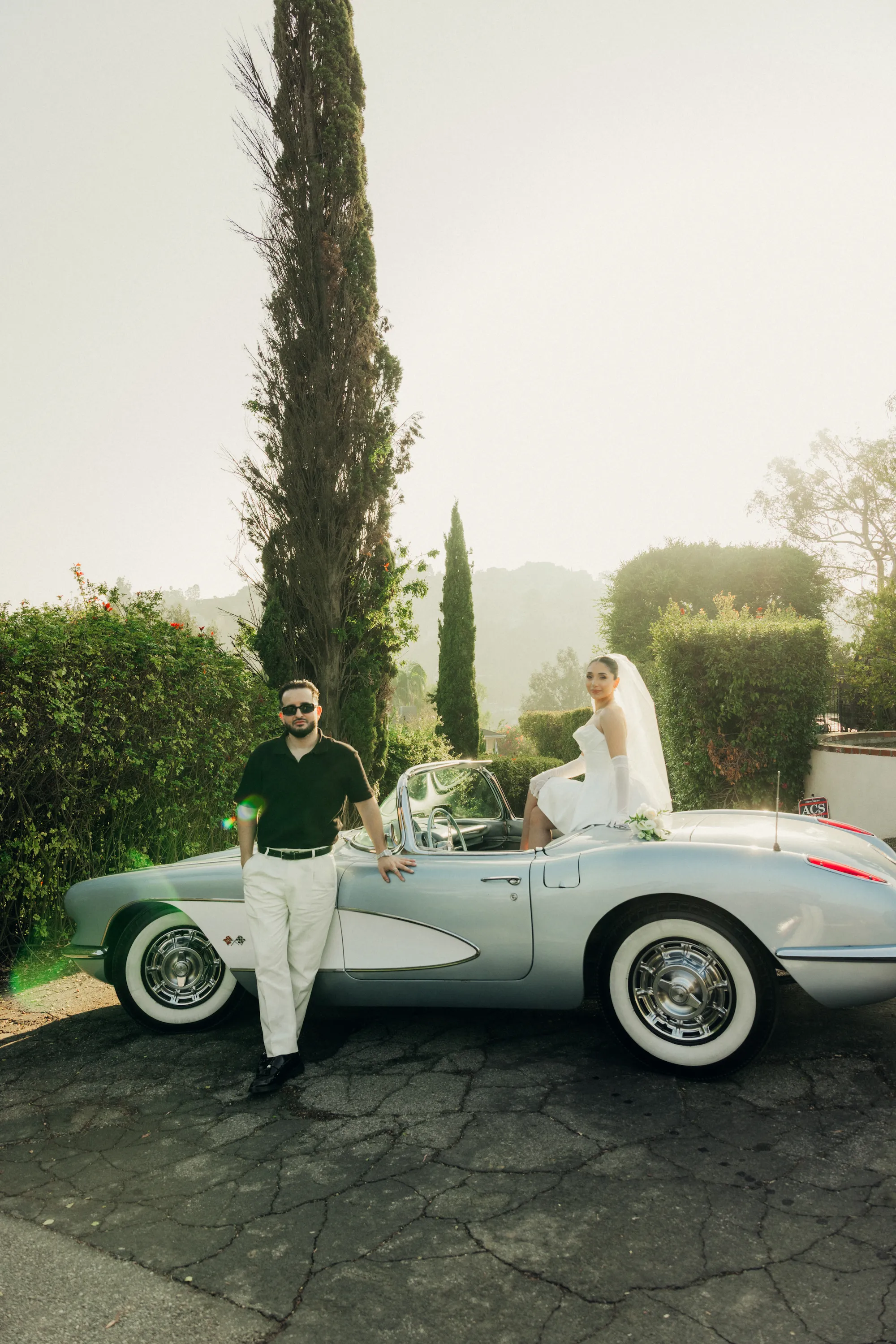 engagement photo outfits at Mulholland Drive Los Angeles, couple in white gown and polo shirt posed with a vintage Corvette convertible