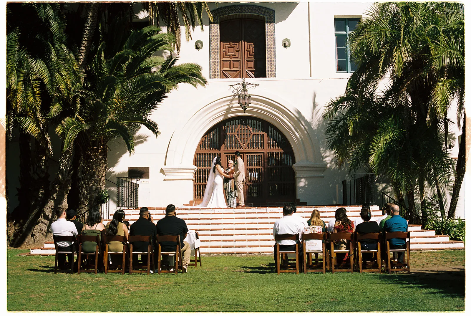Outdoor wedding ceremony on the front steps of the Santa Barbara Courthouse with guests seated in white chairs