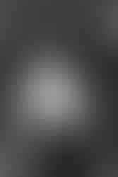 black and white portrait of the groom in suspenders standing inside the winery barrel room before the ceremony