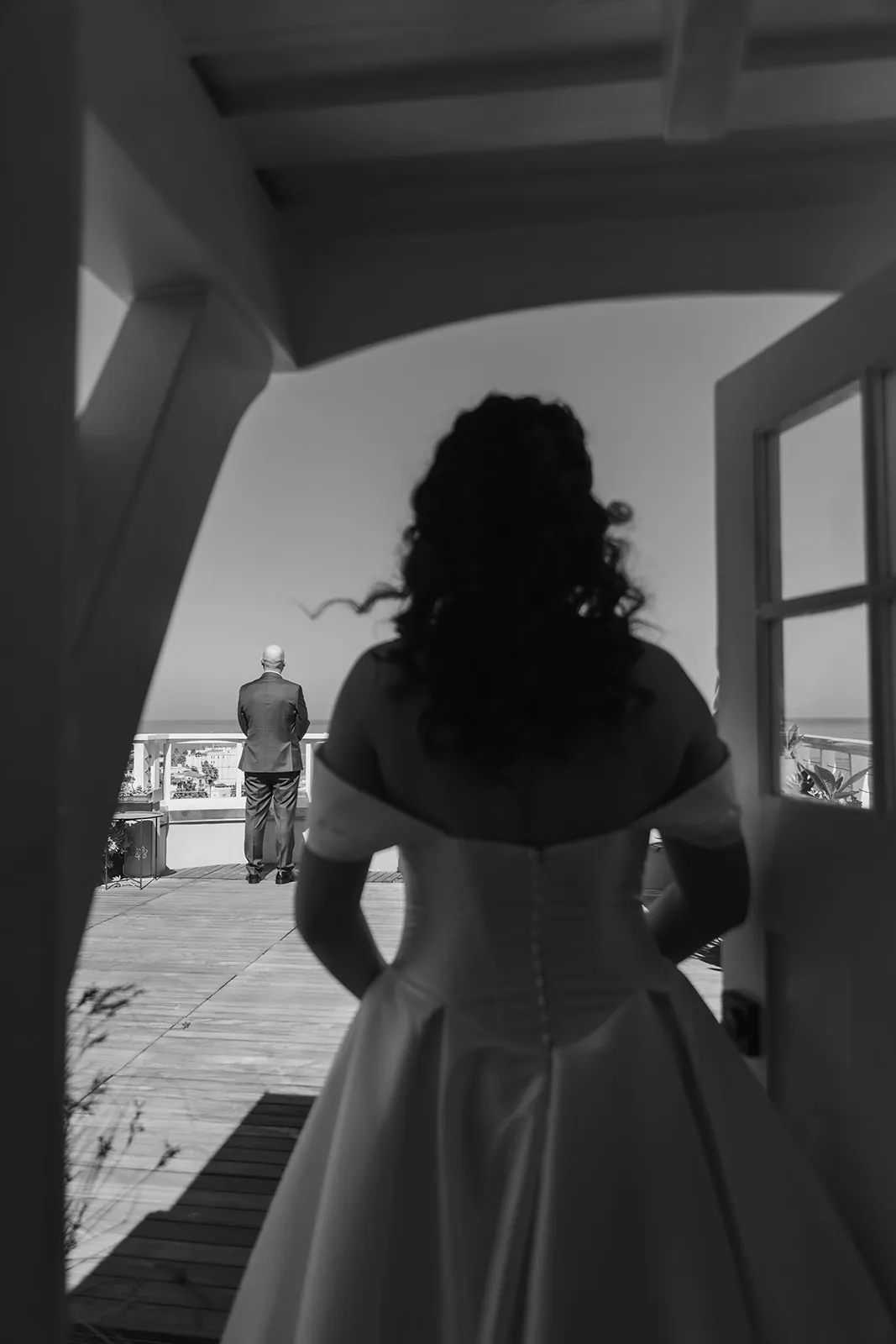 Bride approaching her father from behind on a rooftop overlooking Avalon at their Catalina Island destination wedding, captured in black and white