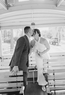 Bride and groom kissing inside the Santa Barbara wedding trolley in black and white with soft window light behind them