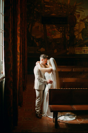 film wedding photographer capturing an intimate first kiss moment with warm indoor light and rich tones