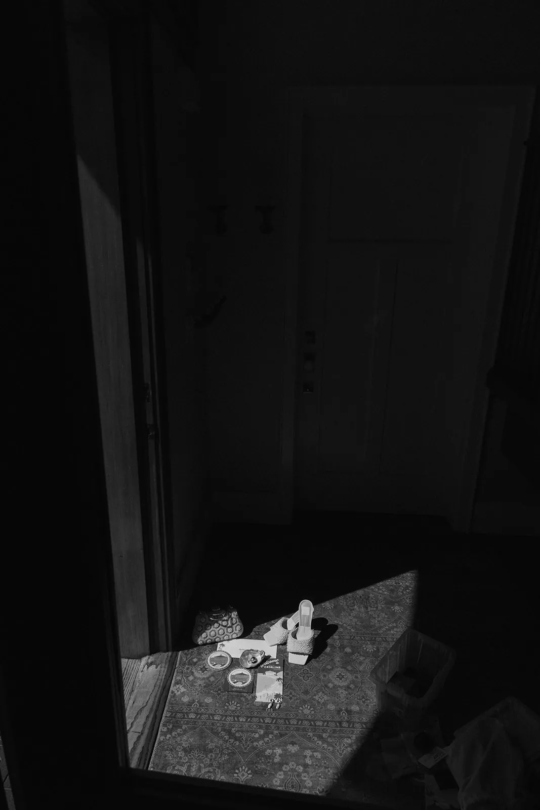 Getting ready detail shot at a Catalina Island Casino wedding — bridal shoes and accessories arranged near the door in dark moody black and white